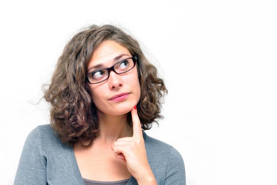 Frau mit Brille guckt fragend nach oben.