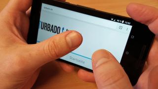 Zwei Hände halten ein Smartphone, auf dessen Display die Internetseite turbado.de zu sehen ist.