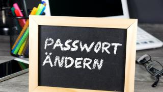 Vor einem Computer steht ein Schild und erinnert daran, das Passwort zu ändern.