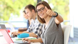 Studenten sitzen in einem Vorlesungsraum vor ihrem Laptop.