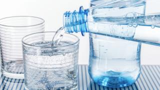 Wasser wird aus einer Flasche eingeschenkt