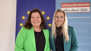 Zwei Frauen vor einem Banner mit der Europa-Flagge und lächeln in die Kamera.