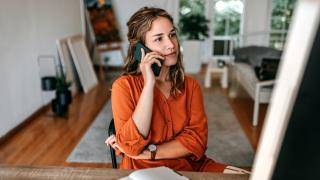 Frau sitzt am Tisch und telefoniert