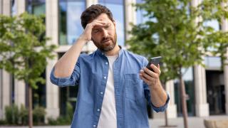 Mann schaut verärgert auf sein Smartphone.