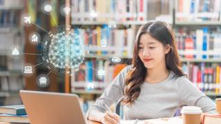 Frau sitzt am Laptop und lächelt.