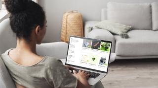 Frau sitzt vor Laptop, auf welchem ein Kleinanzeigen-Portal geöffnet ist.