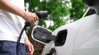 Mann lädt sein E-Auto.