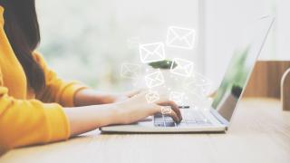 Frau an Laptop, die Mails schreibt.