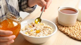 Eine Frau macht Honig in ihr Frühstück.