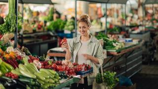 Frau an einem Marktstand mit Gemüse