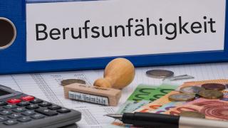 Ein Aktenordner mit der Aufschrift "Berufsunfähigkeit", ein Taschenrechner, ein Stempel und Bargeld