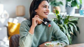 Lächelnde Frau isst einen Salat mit Erdbeeren