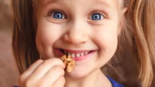 Ein Mädchen isst eine Walnuss