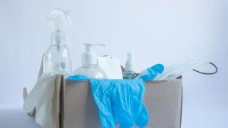 Karton mit Pflegemitteln wie Einmalhandschuhen, OP-Maske, Spray
