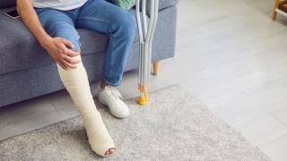 Mann sitzt auf Sofa mit verletztem Bein