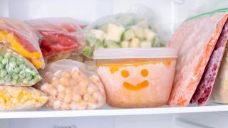 Ein offenes Fach in einem Gefrierschrank. Es sind verpackte Lebensmittel zu sehen.