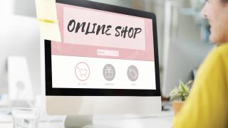 Eine Frau sitzt am PC beim Online Shopping