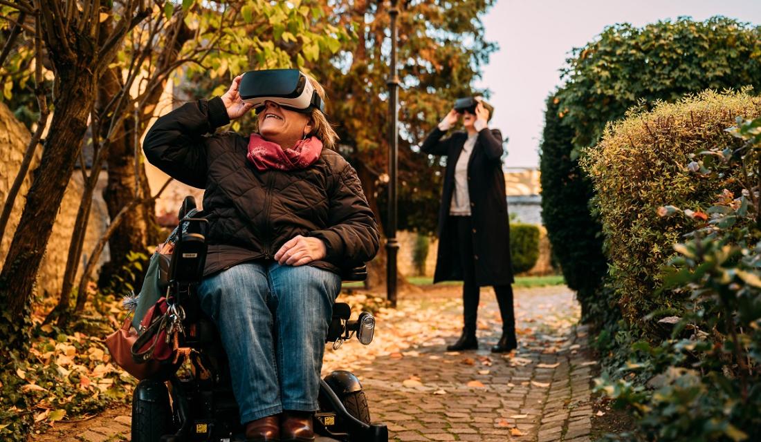 Frau im Rollstuhl schaut durch eine Virtual Reality Brille.