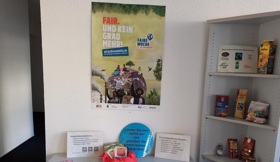 Ein Tisch mit verschiedenen Infomaterialien zum Thema: Fair Trade. Rechts steht noch ein Regal mit einigen Fair-Trade Produkten wie Kaffee, Saft und Schokolade..