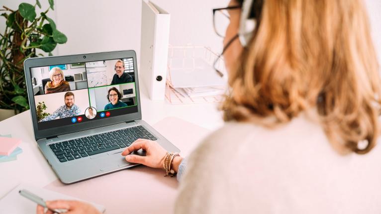 Frau vor Laptop spricht in einer Videokonferenz.